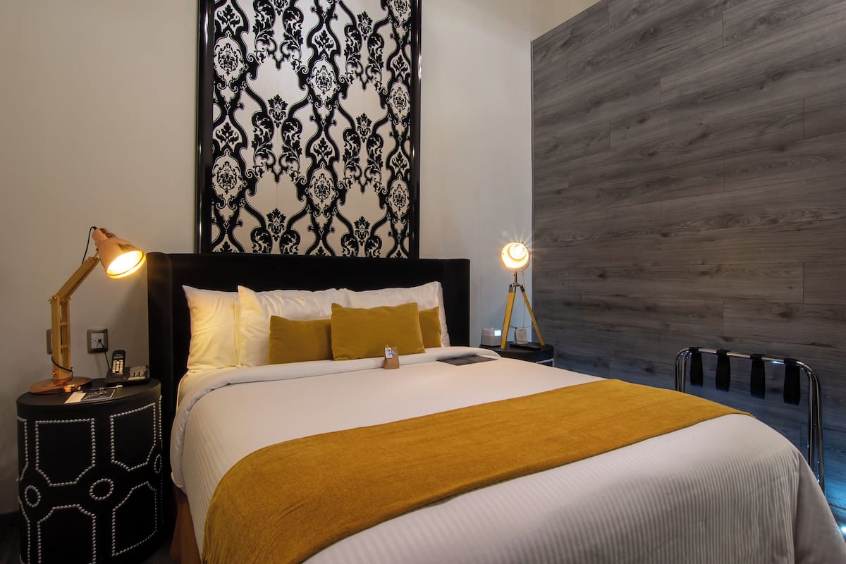 Una cama bien tendida con una combinación de colores blanco y amarillo, un panel decorativo en la pared y un suelo de madera.