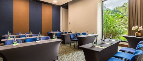 A conference room with a long table, blue chairs, and a carpeted floor.