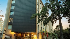 A modern hotel with a prominent dark facade, large windows, and a well-lit entrance.
