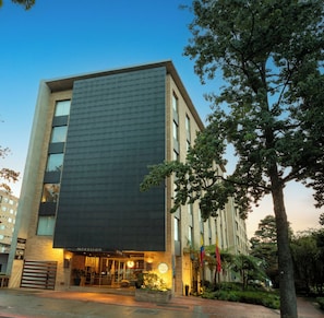 A modern hotel with a prominent dark facade, large windows, and a well-lit entrance.