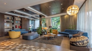 A modern living room with a sofa, ottoman, coffee table, and a large decorative vase.