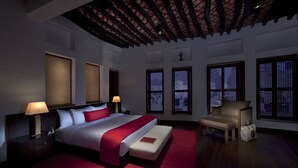 Una habitación de hotel moderna con una cama grande, techo de madera y ventanas tradicionales.