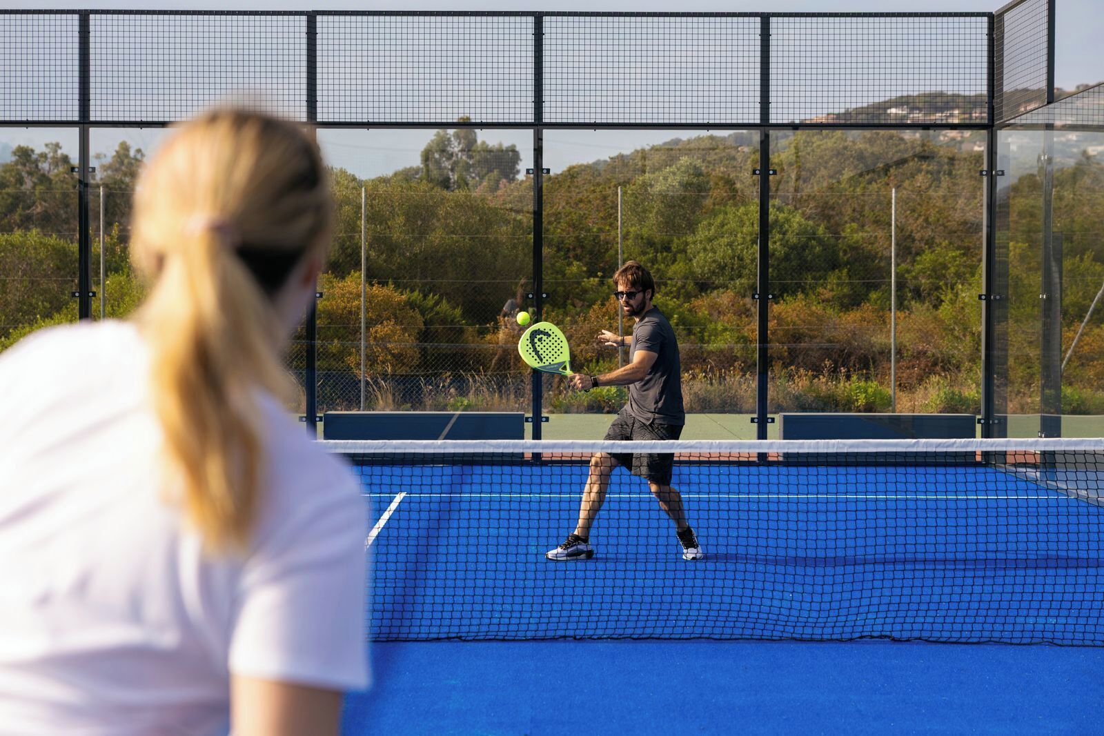 Ein Tennisplatz mit Netz in der Mitte, umgeben von einem Zaun.