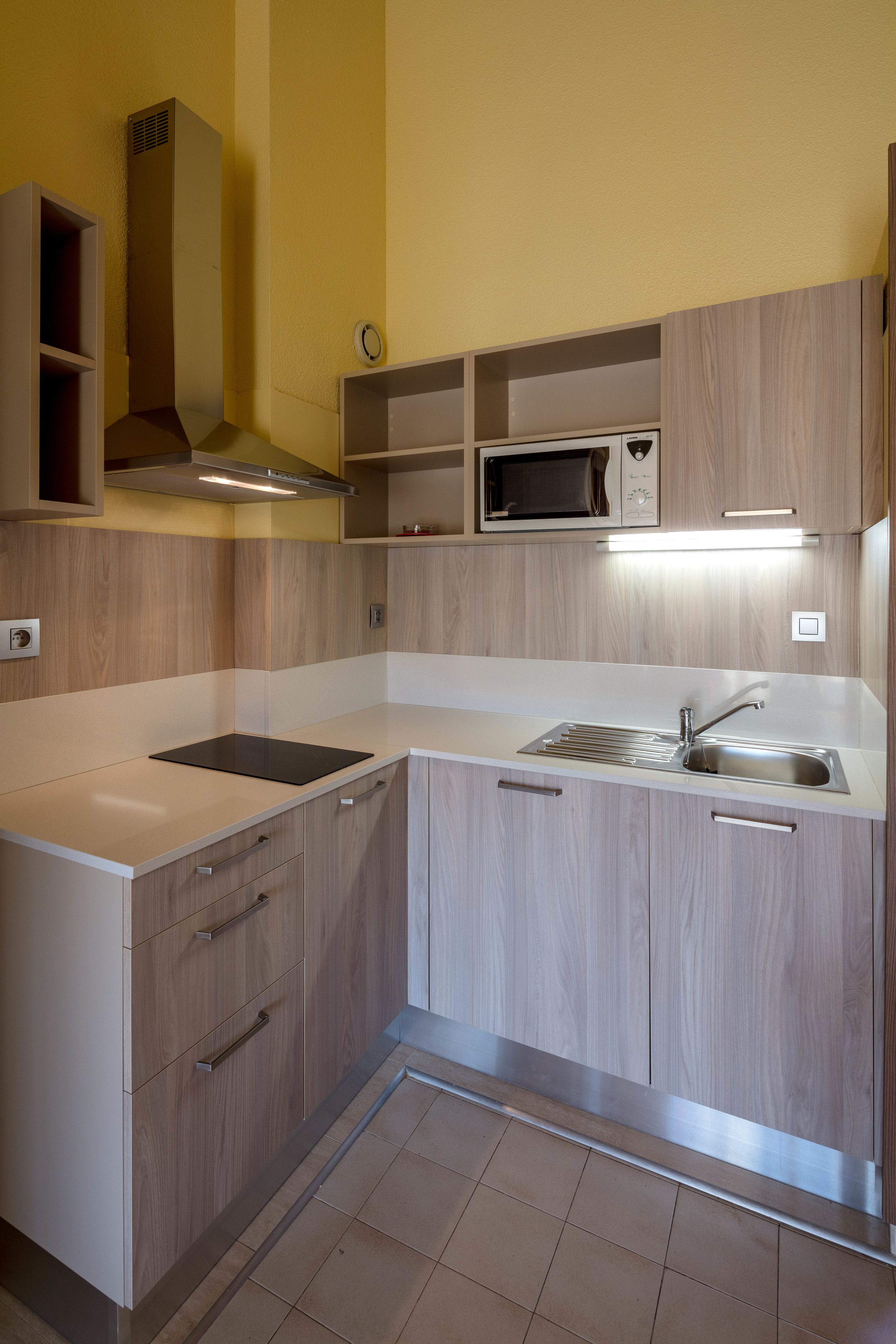 A compact kitchen with a microwave, sink, and built-in cabinets.