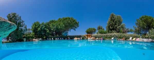 A clear blue swimming pool surrounded by lounge chairs and trees. - Résidence Paese Serenu (Porto-Vecchio)
