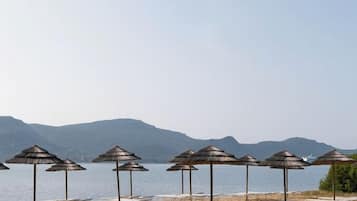 En privat strand, liggestole, parasoller, volleyball