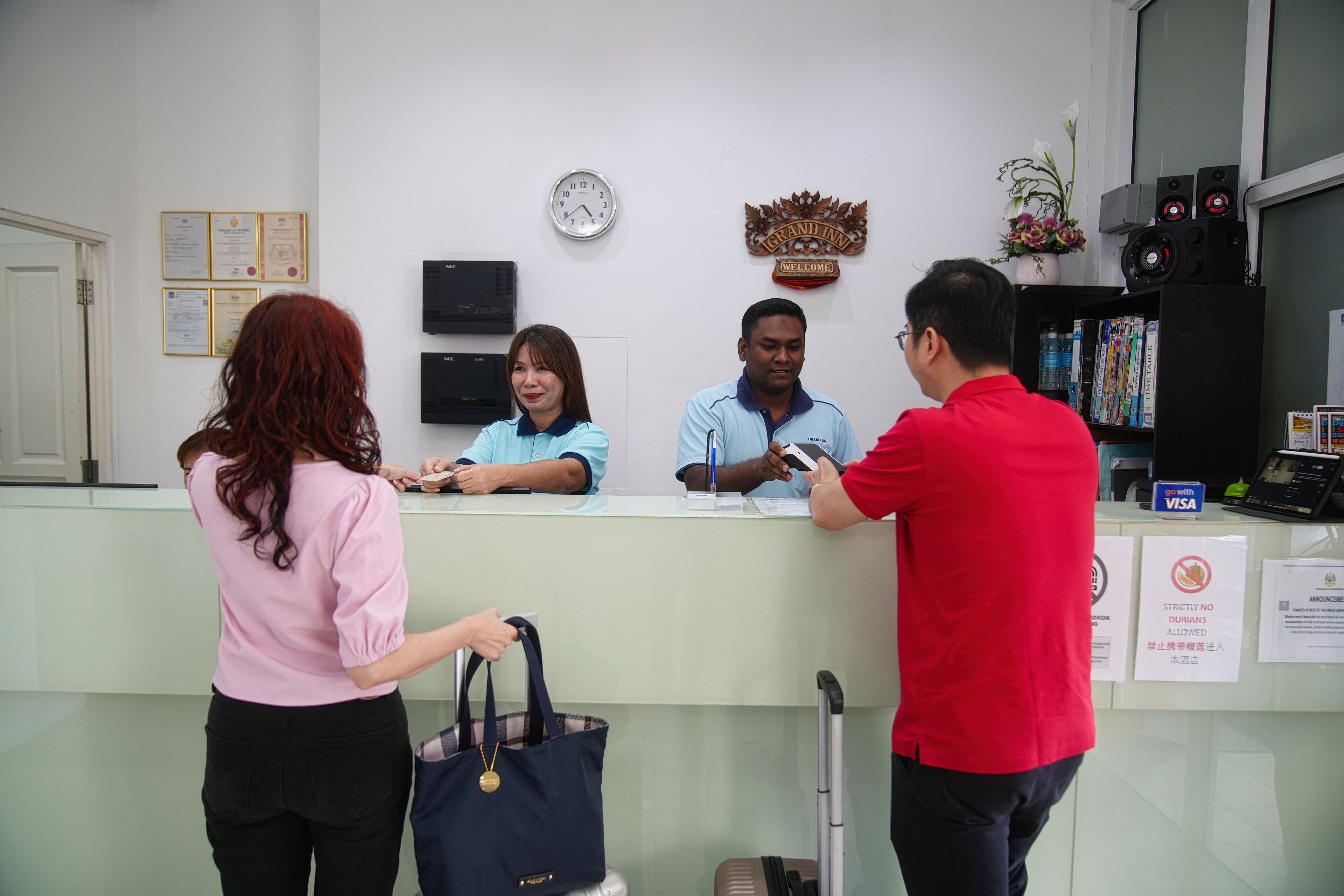 A reception desk with a clock, certificates, and a 'No Durians Allowed' sign.
