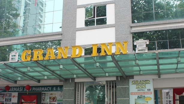 Un hotel llamado Grand Inn con una fachada moderna de vidrio y un letrero amarillo llamativo.