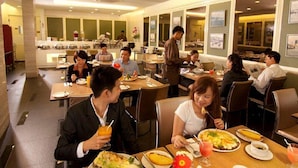 A restaurant with multiple tables and chairs, a counter with staff, and framed pictures on the walls. - Sentral Georgetown (George Town)