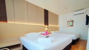 A hotel room with two beds, a wooden floor, a wall-mounted air conditioner, and a small picture frame. - Sentral Georgetown (George Town)