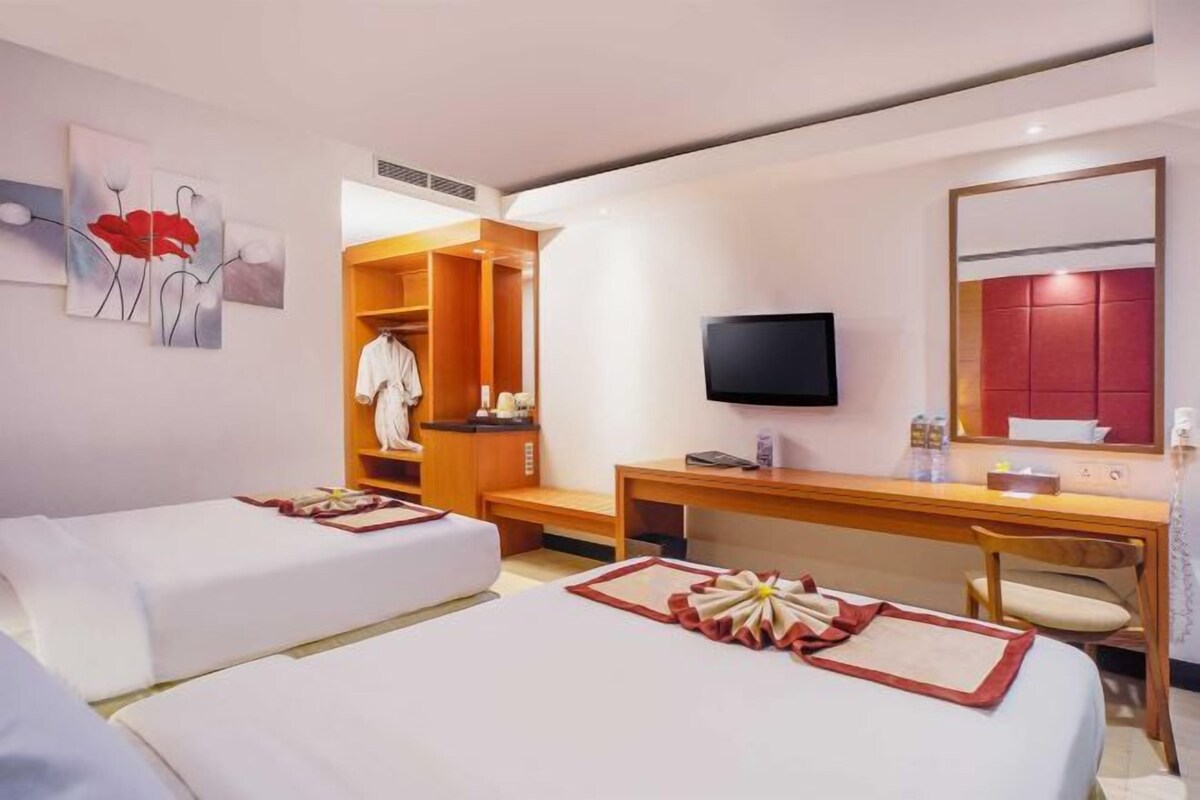Habitación de hotel con dos camas, un escritorio, televisión y armario.