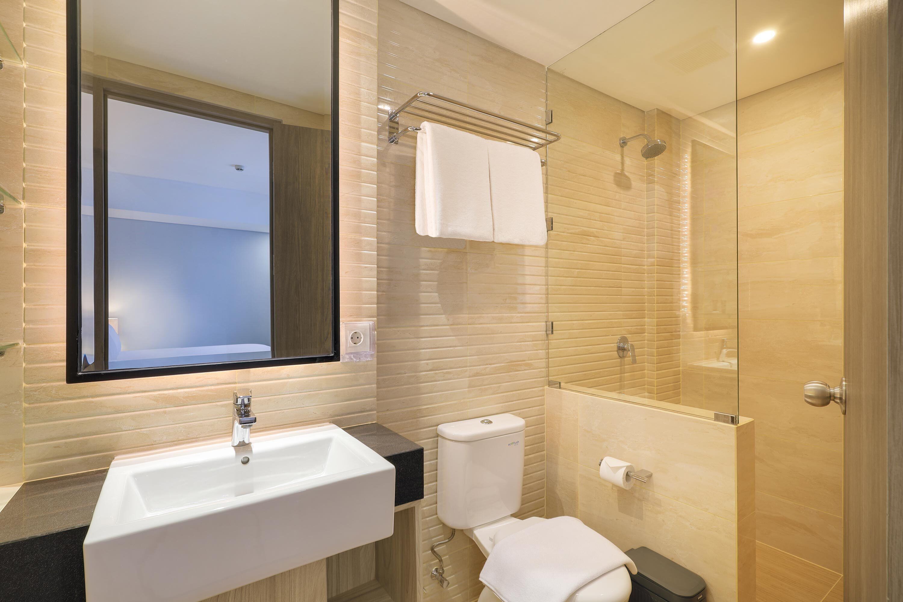 A modern bathroom with a large sink, toilet, and glass-enclosed shower.