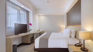 Ein modernes Hotelzimmer mit einem großen Bett, einem Fernseher, einem Schreibtisch und einer Lampe.