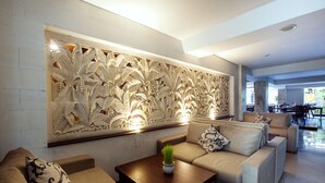 Una sala moderna con un sofá, una mesita de centro y un panel decorativo en la pared.