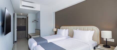 Une chambre d’hôtel moderne avec un grand lit, des tables de chevet, un téléviseur et un porte-manteau.
