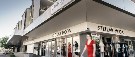 Un hotel con fachada moderna, mostrando los nombres 'Grand Hotel' y 'Stellar Moda' de manera destacada.