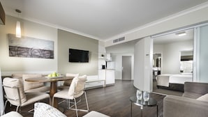 A modern hotel room with a dining area, a bed, and a kitchenette. - Grand Hotel and Apartments Townsville (South Townsville)