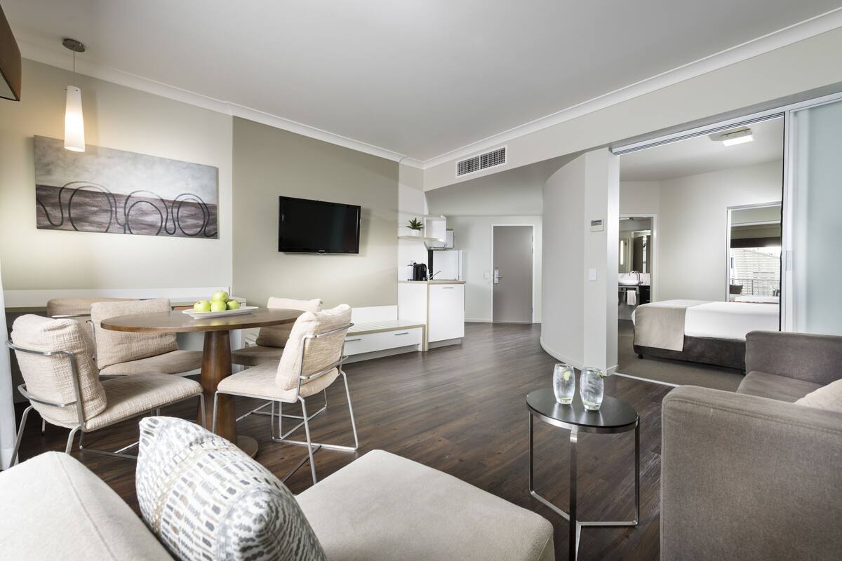 Ein modernes Hotelzimmer mit Essbereich, Bett und einer Küchenzeile.