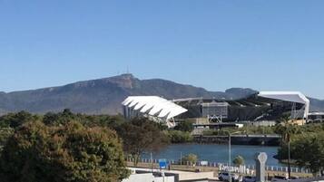 A modern building with a unique roof design, situated near a body of water and a mountain in the background.
