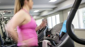 Une salle de sport équipée de matériel d’exercice et d’un tapis de course.