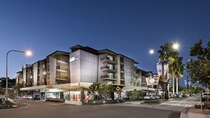 A multi-story hotel with a modern design, featuring balconies and a ground-level retail space. - Grand Hotel and Apartments Townsville (South Townsville)