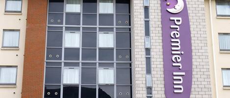 Un hotel Premier Inn con fachada curva, ventanas amplias y un letrero morado llamativo.