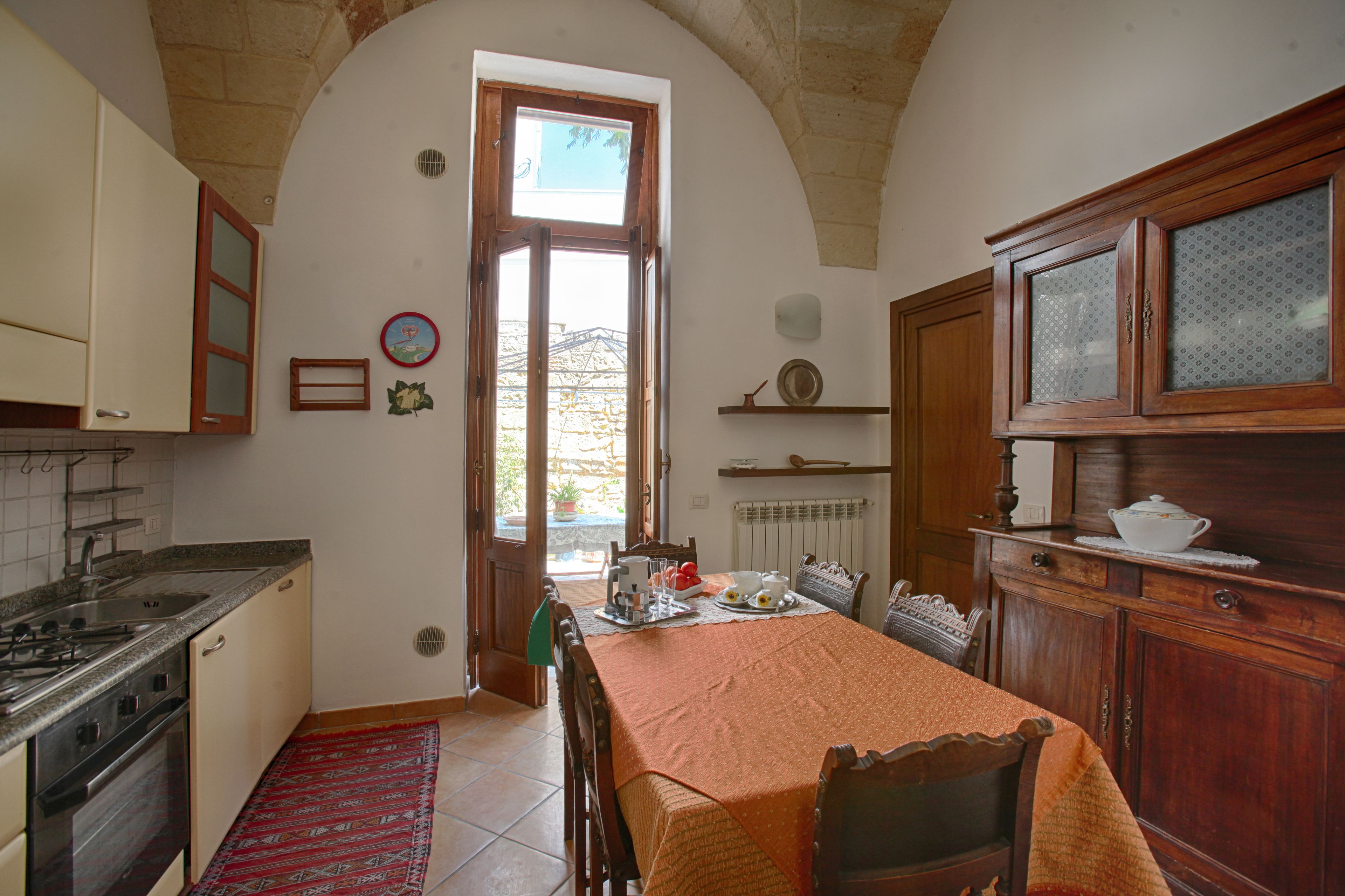 Una cocina con mesa, armarios de madera y ventana con vistas.