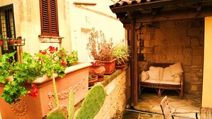 A courtyard with potted plants, a wicker chair, and a stone wall.