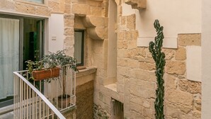 A stone courtyard with a white railing, a potted plant, and a cactus.