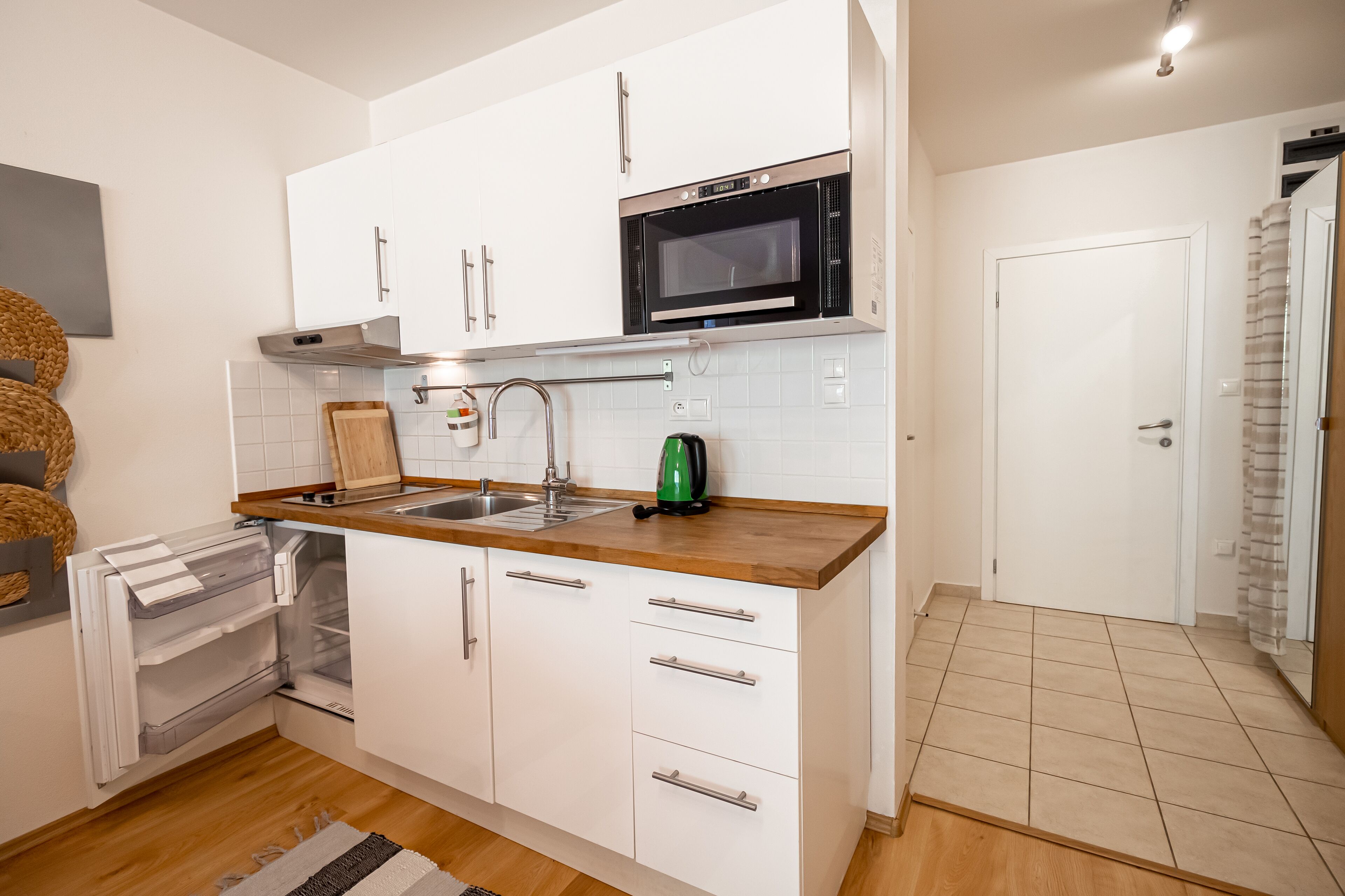 A compact kitchen with white cabinets, a stainless steel oven, and a wooden countertop.