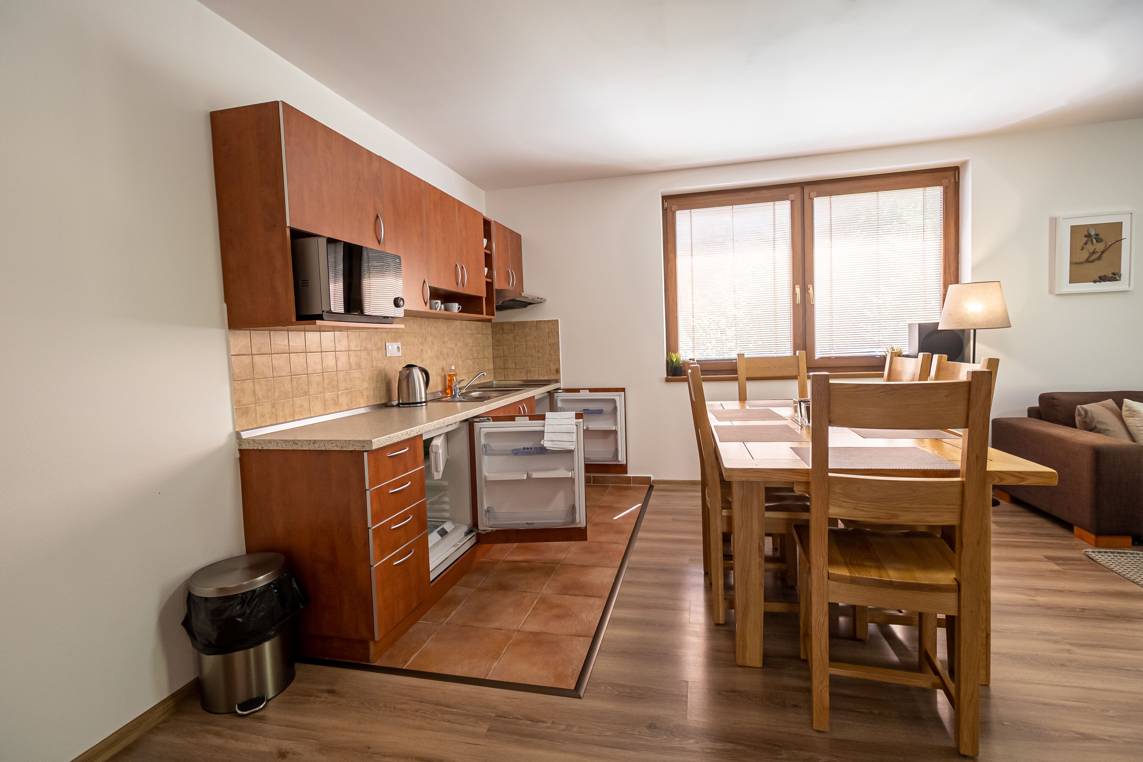 A compact kitchen with wooden cabinets, a dining table, and a window.