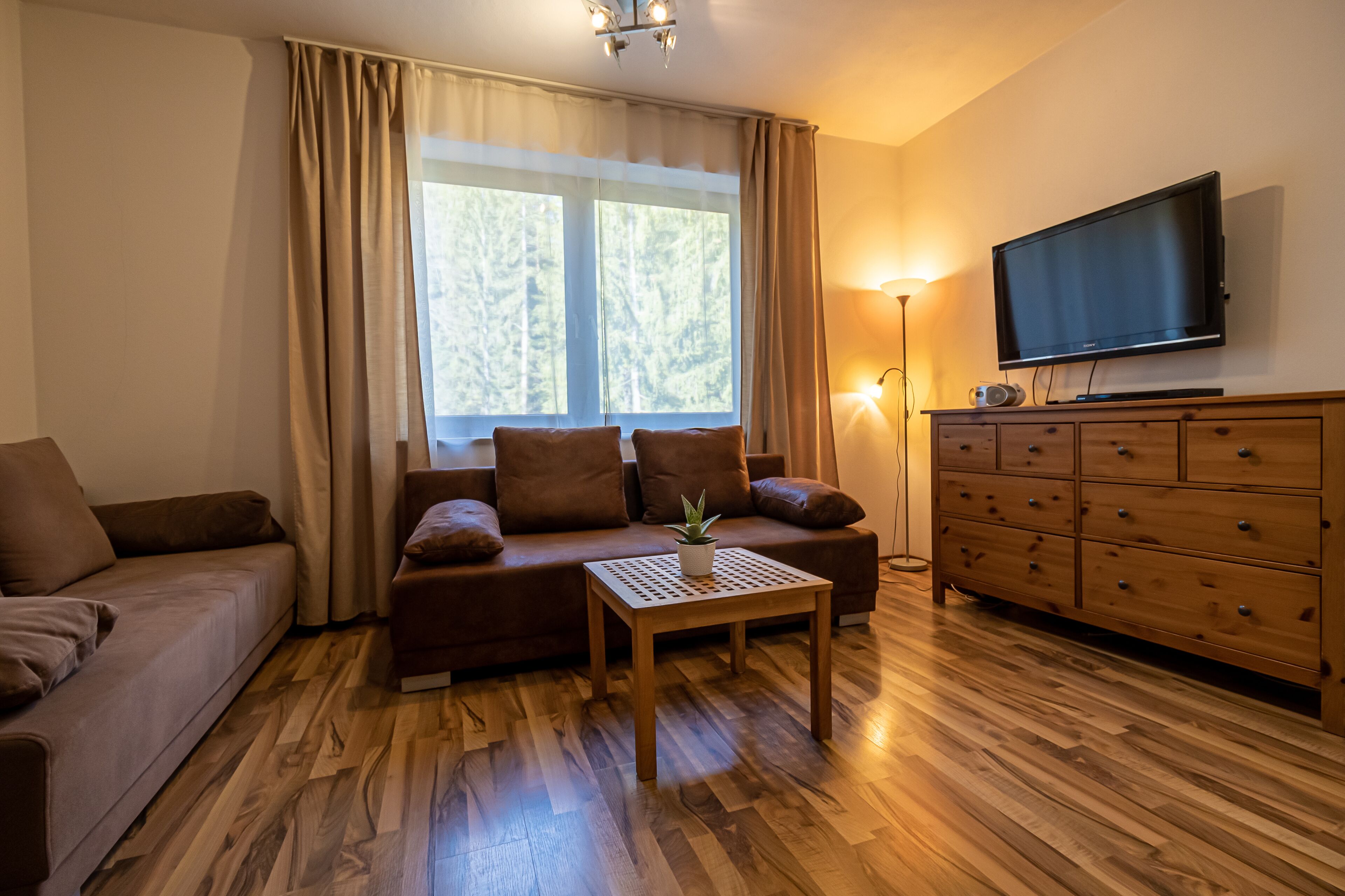 A cozy living room with a sofa, a coffee table, a TV, and a wooden cabinet.