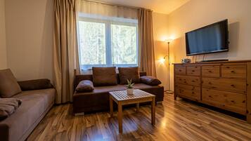 A cozy living room with a sofa, a coffee table, a TV, and a wooden cabinet.