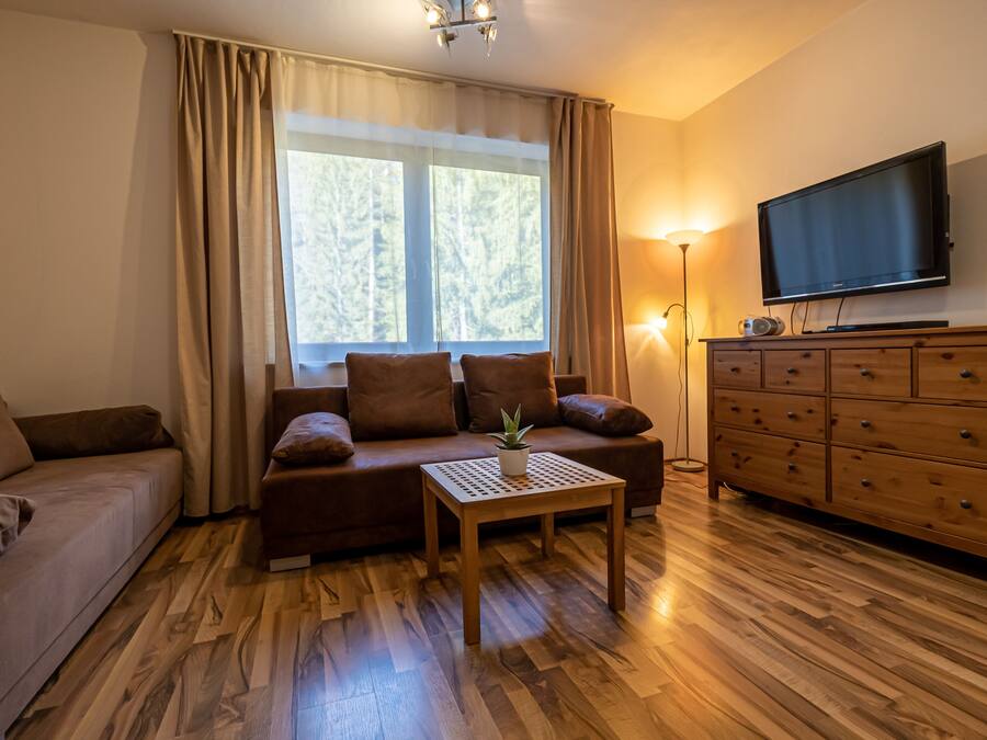 Een knusse woonkamer met een bank, een salontafel, een televisie en een houten kast.