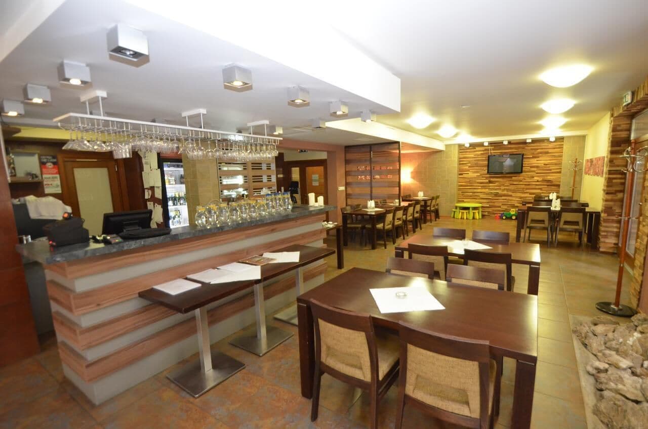 A restaurant with a bar area, multiple tables, and chairs.