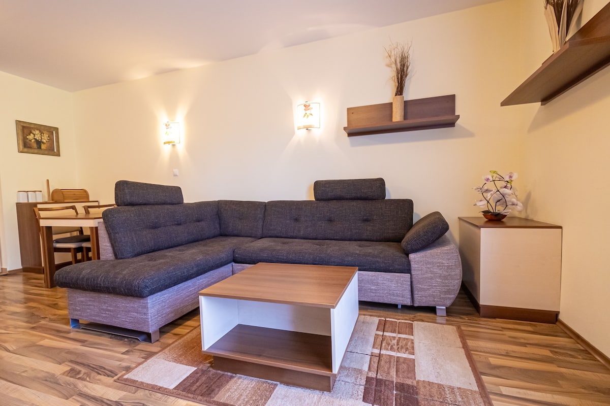 A modern living room with a sectional sofa, a wooden coffee table, and a small side table with a vase.