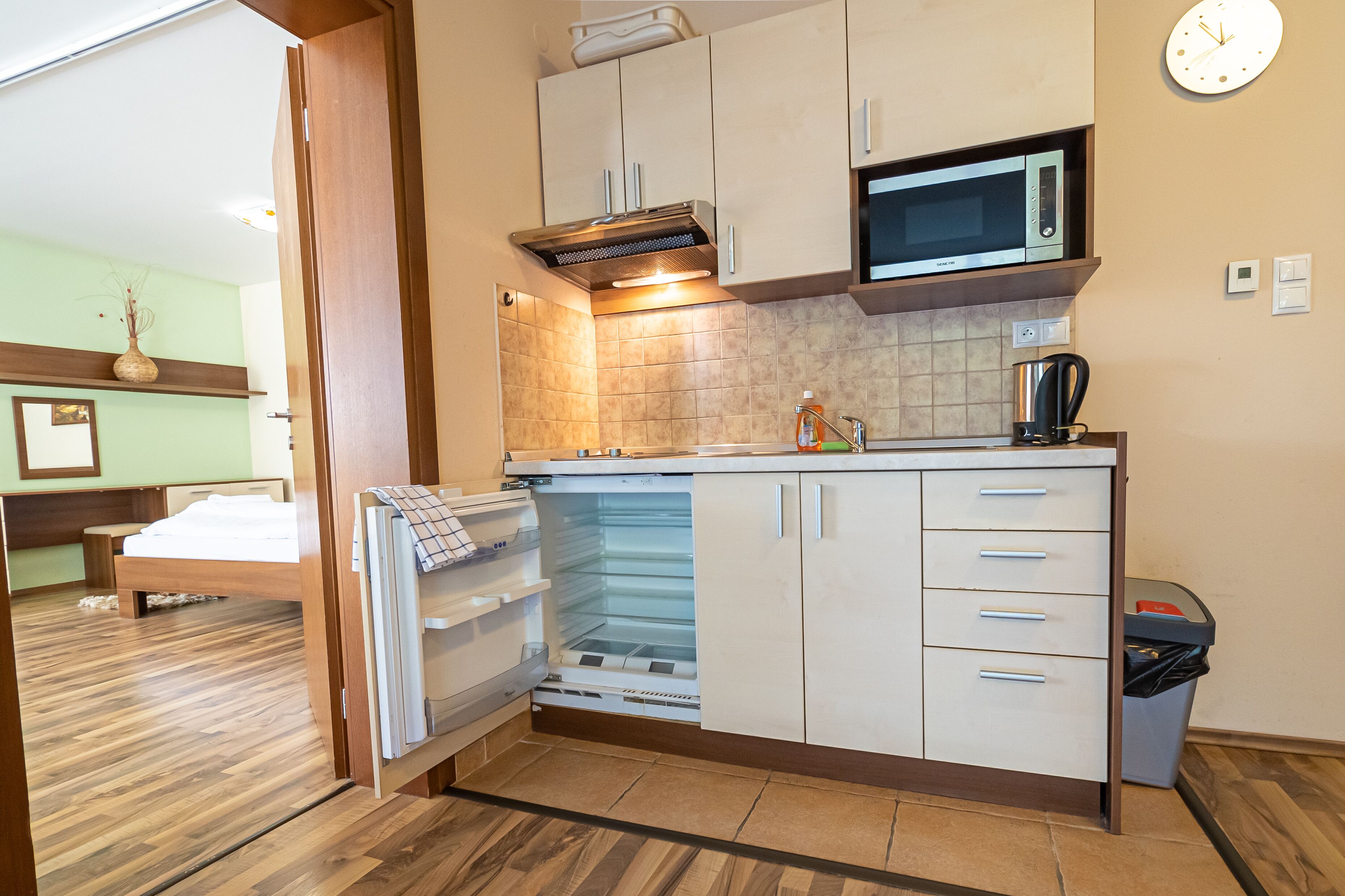 A compact kitchen with a microwave, a coffee maker, and a trash bin.