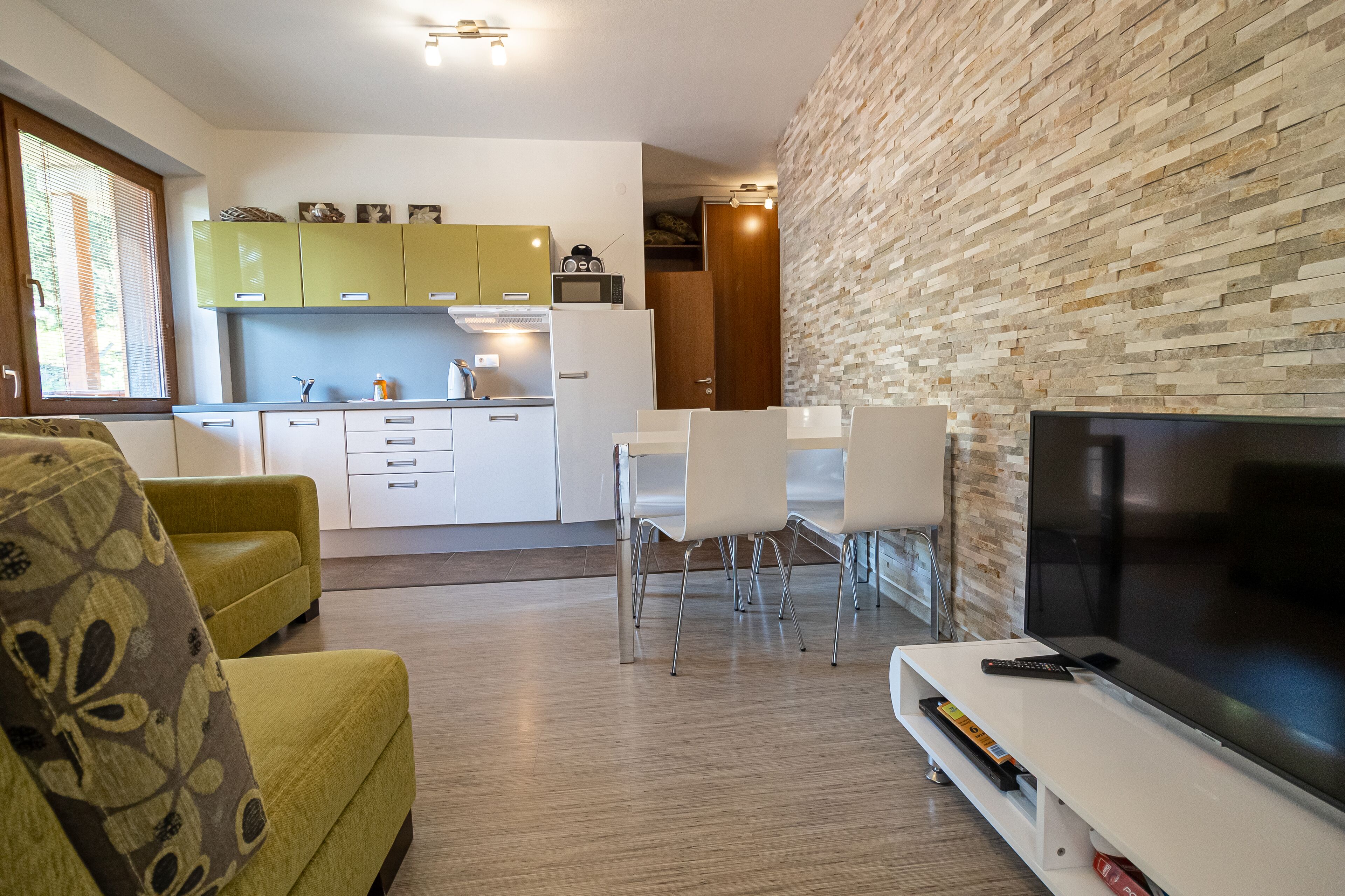 Een moderne woonkamer met een bank, een televisie en een eethoek met stoelen en een tafel.