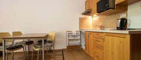 A compact kitchen with wooden cabinets, a built-in microwave, and a small countertop.