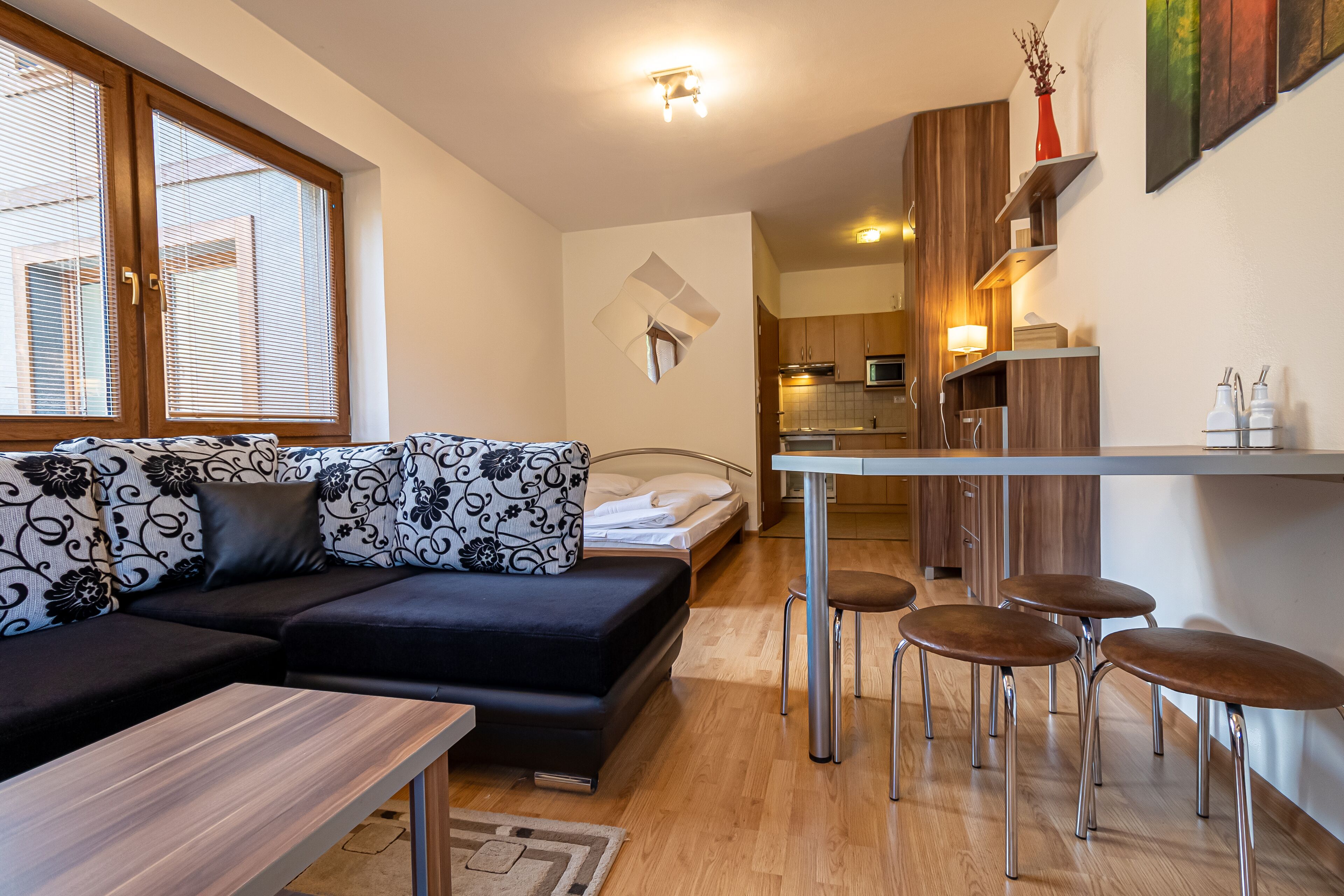 A modern, compact living space with a sofa, a small dining table, and a kitchen area.