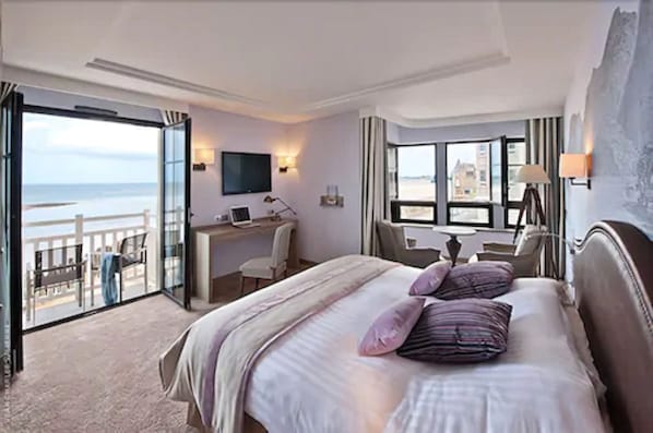 Habitación de hotel con cama, escritorio y vista al mar.