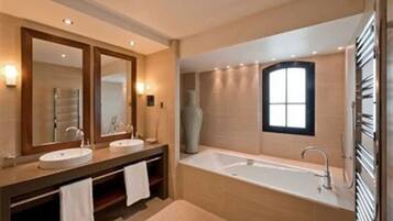 A modern bathroom with two sinks, a large bathtub, and a large mirror.