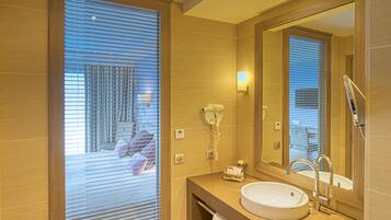 A modern bathroom with a large mirror, a sink, and a hairdryer on the wall.