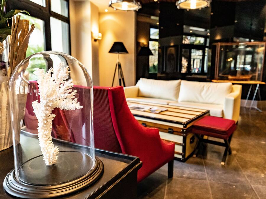 A modern interior with a white sofa, red armchair, and a glass display case with a decorative item.