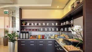 Una cocina moderna con muebles oscuros, electrodomésticos de acero inoxidable y diversas opciones para el desayuno a la vista.