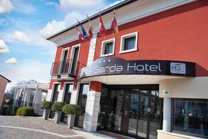 Exterior del hotel Gacda, con fachada roja, varias banderas y un balcón.