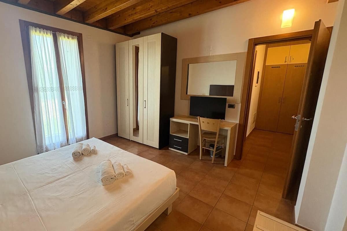 A bedroom with a bed, a desk, a chair, a wardrobe, and a mirror.