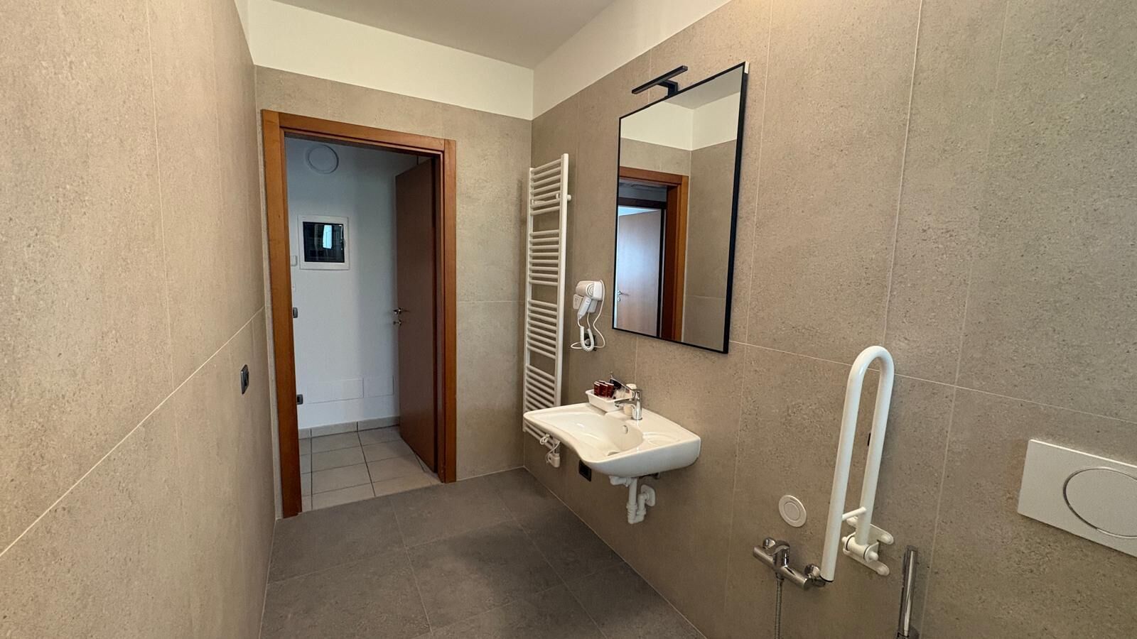 Une salle de bain équipée d’un lavabo, d’un miroir, d’un porte-serviettes et d’une douche.