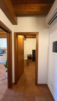 Un pasillo con puertas de madera, suelo de baldosas y un equipo de aire acondicionado visible.