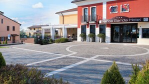Un hotel con fachada roja, un área de estar al aire libre techada y un patio empedrado.
